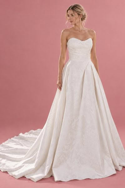Kimberley wedding dress, front view against a dusty pink studio background