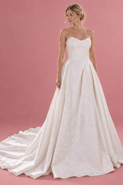 Kimberley wedding dress, front view against a dusty pink studio background